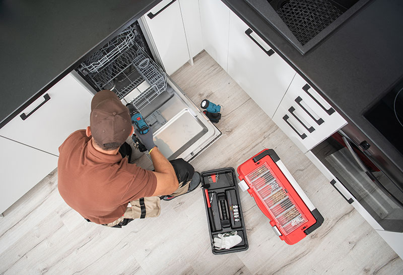Technician Installing Dishwasher Inside Residential Apartment Ki